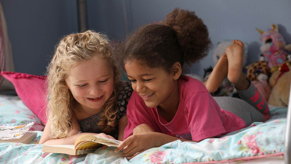 Children reading on a bed together
